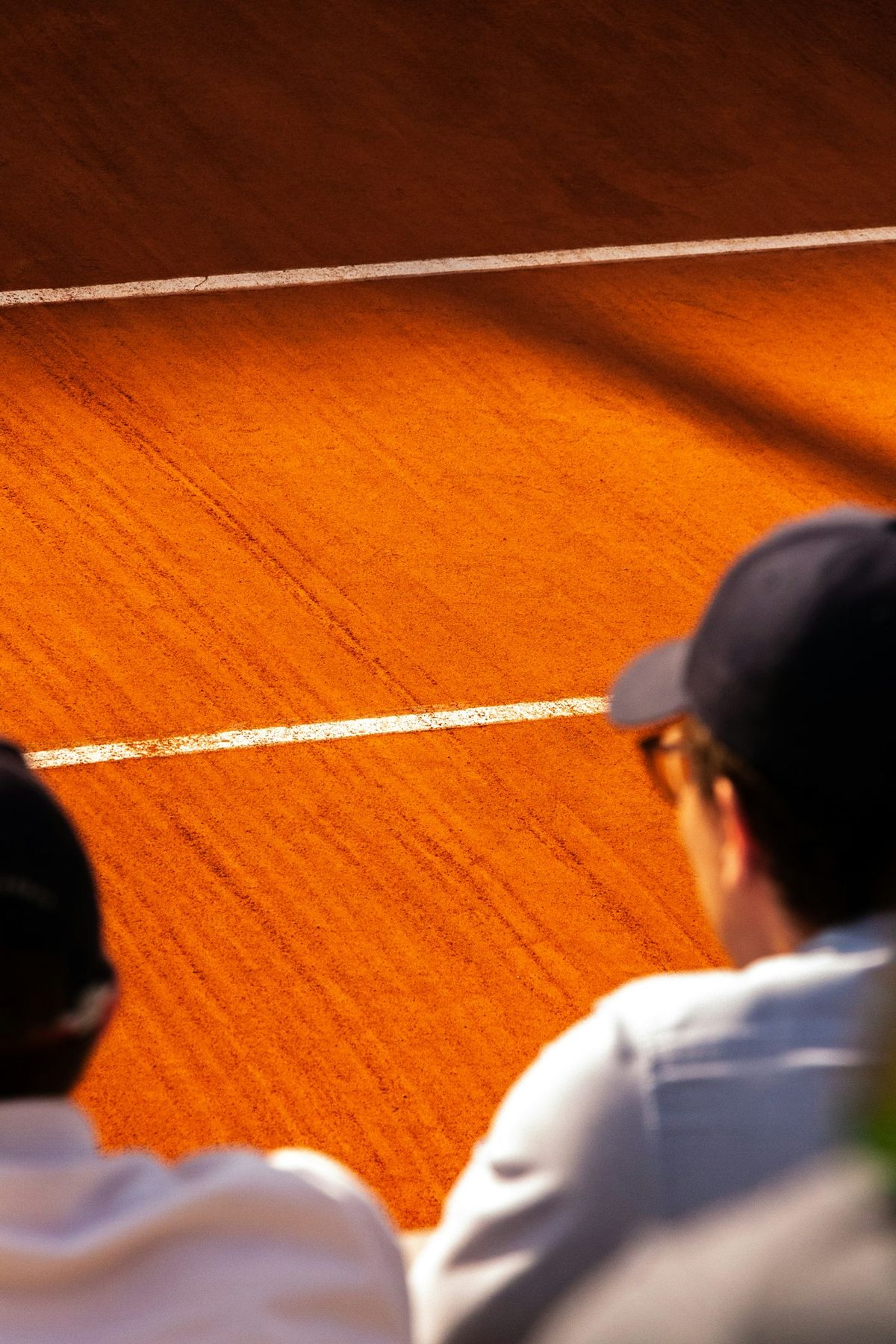 Guests watch a clay court match from front row seats